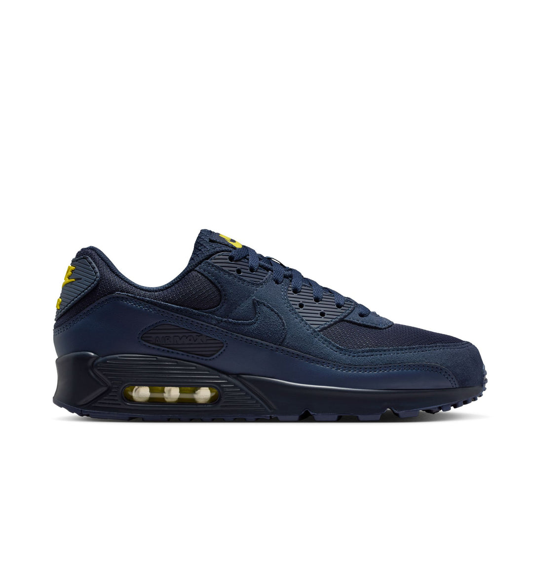 Navy blue sneaker with yellow accents on a white background