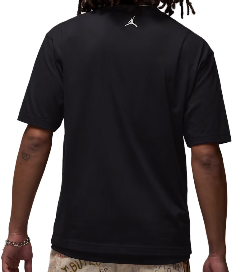 Black Jordan Brooklyn t-shirt with a logo on the back, worn by a person.