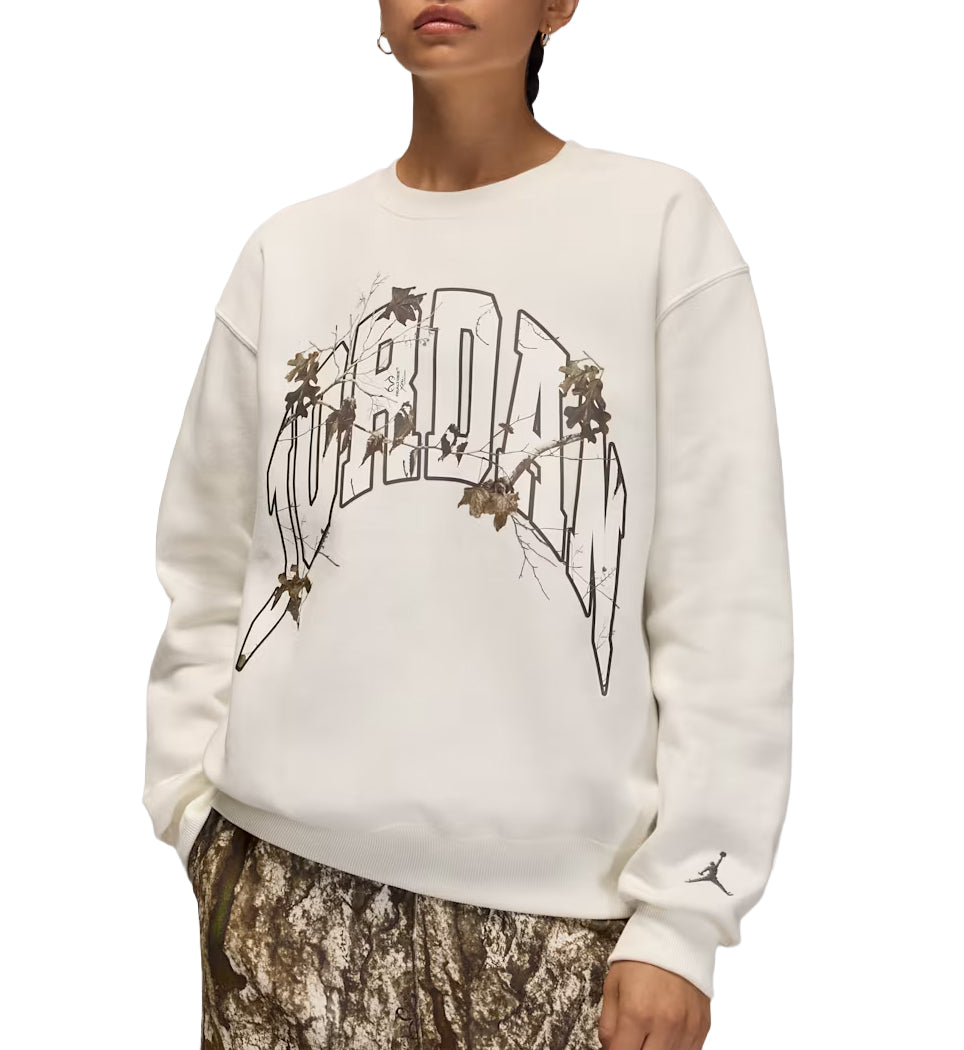 Person wearing a cream Jordan Brooklyn Fleece Women’s Realtree Crew-Neck Sweatshirt with a graphic design on a white background