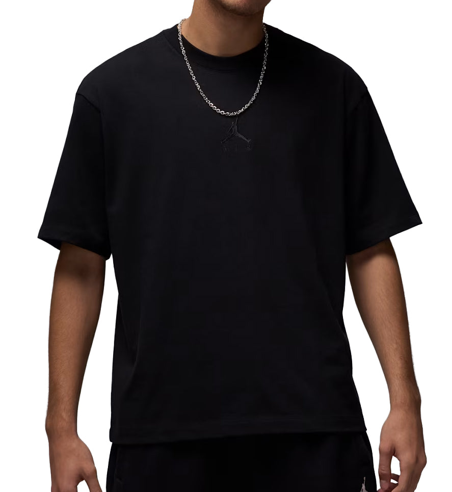 Person wearing a black Jordan Oversized Essentials t-shirt on a white background