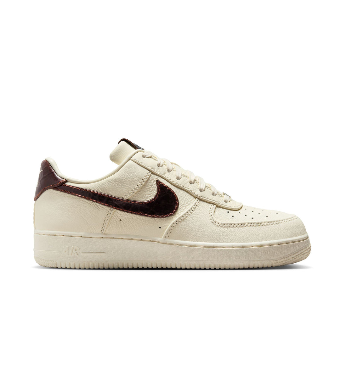 Beige sneaker with brown swoosh logo on a white background