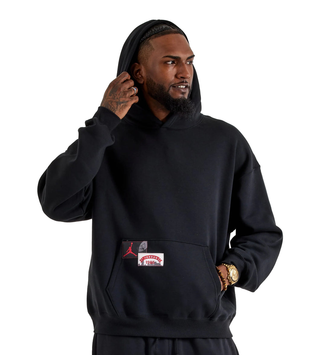 Man wearing a black Jordan Brooklyn Oversized Pullover Fleece hoodie with a Jordan brand logo on a white background