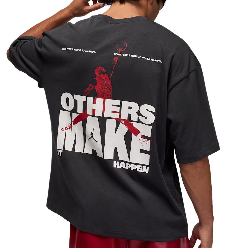 Black Jordan Oversized Reissue t-shirt with red and white graphic design on the back, worn by a person.