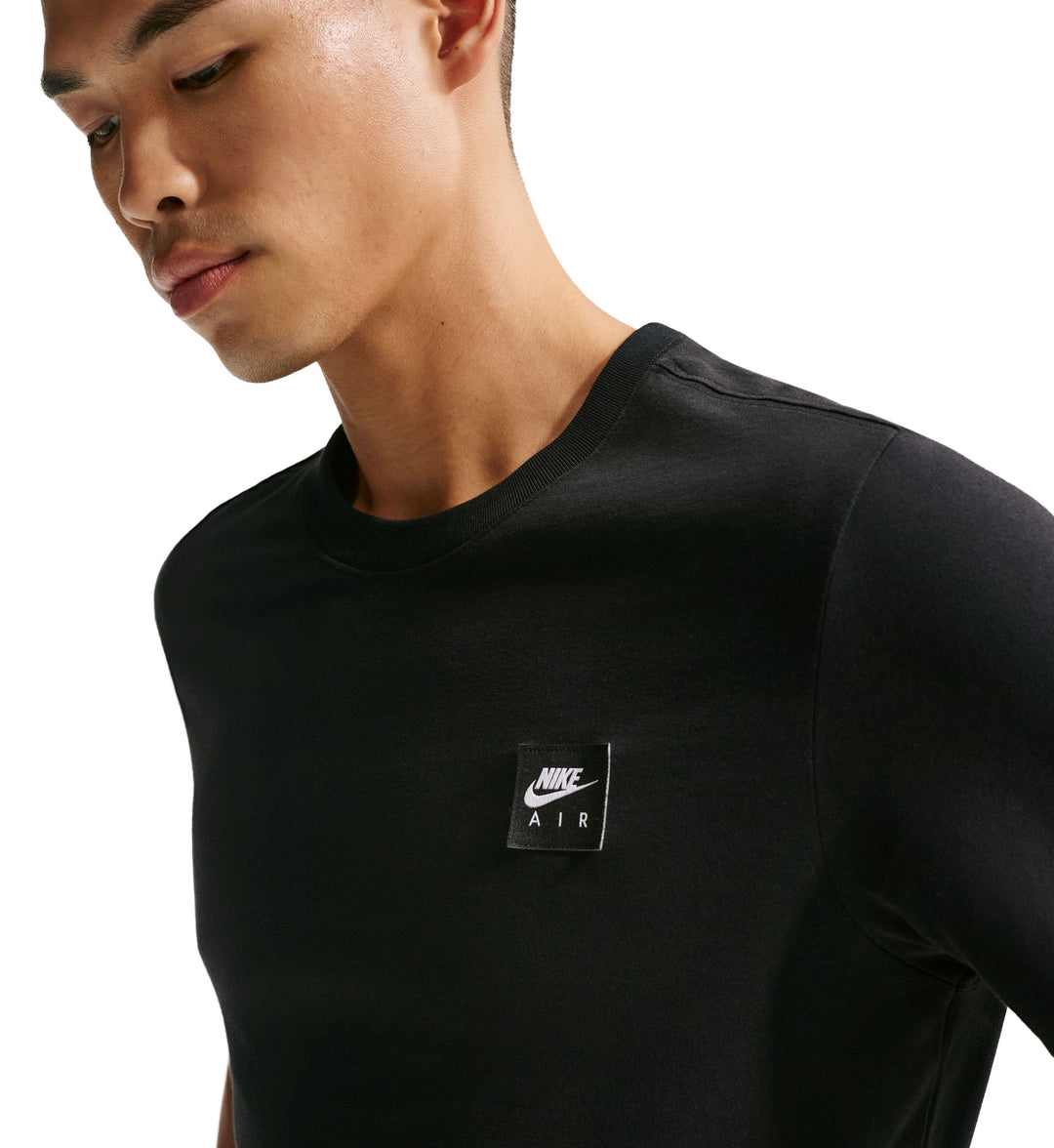 Person wearing a black Nike Sportswear T-Shirt  with a logo on a white background