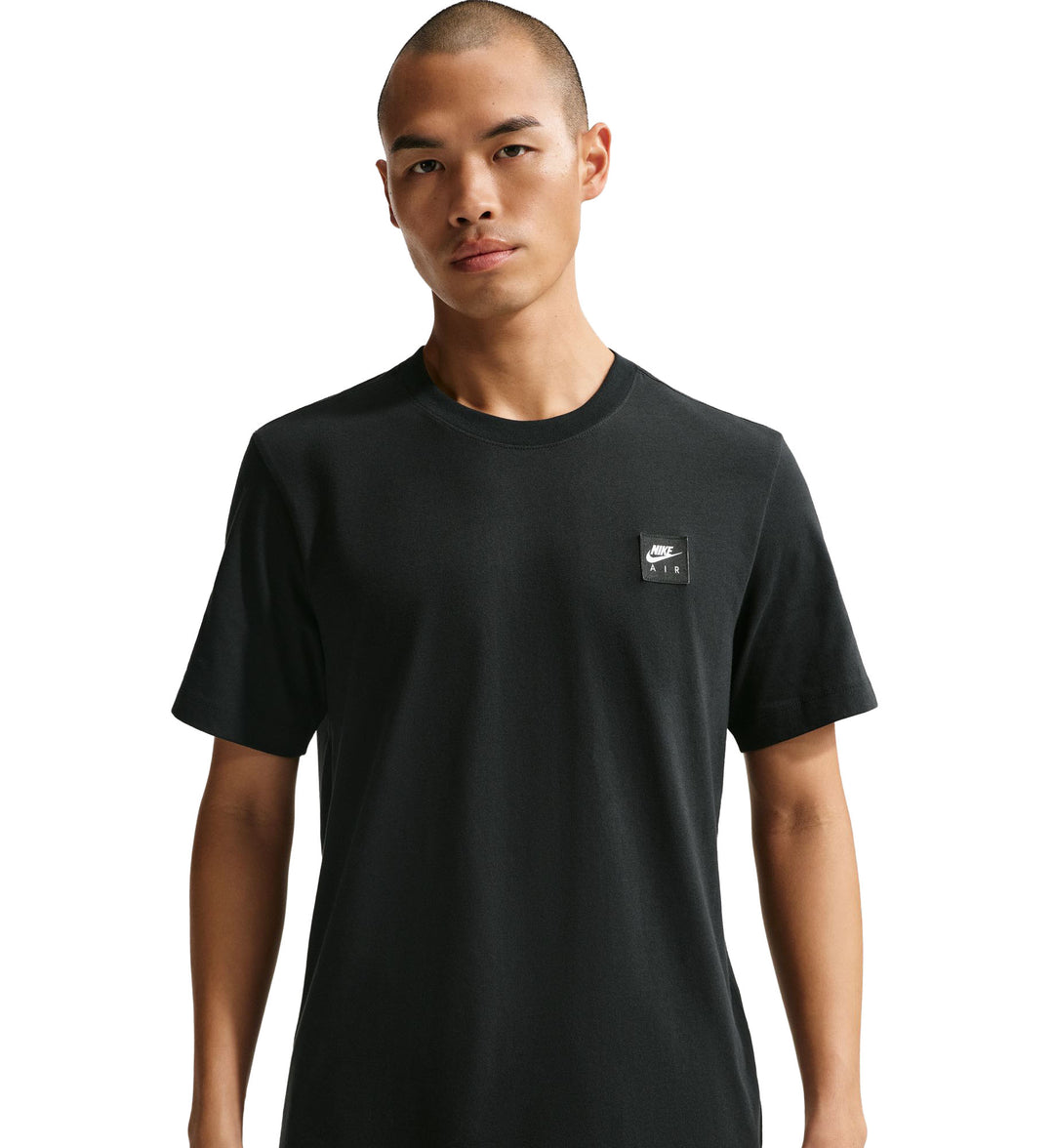 Man wearing a black Nike Sportswear T-Shirt with a small logo on a white background