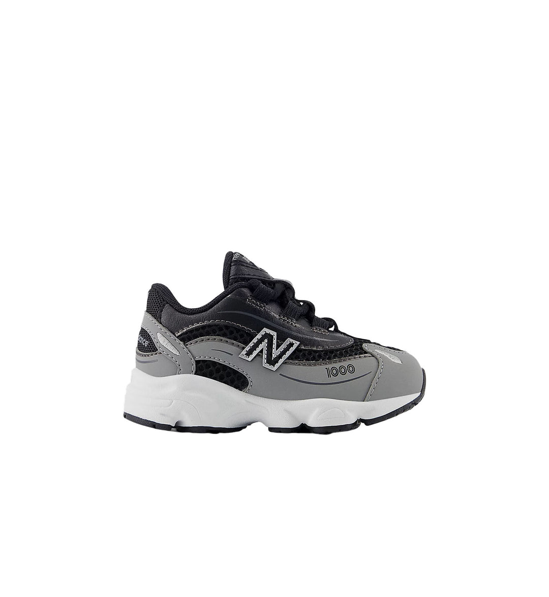 Kids grey and black New Balance shoe with white background.